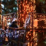 Close-up of glowing lights adorning a suspension bridge at Capilano Suspension Bridge Park, with the magical ambiance of Canyon Lights shining through the dark forest.