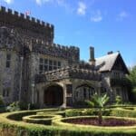 Stone turrets and arched doorways decorate Hatley Castle, framed by trimmed hedges and a round garden bed in front. Visiting this historic site adds a regal touch to any weekend trip itinerary in Victoria, BC.