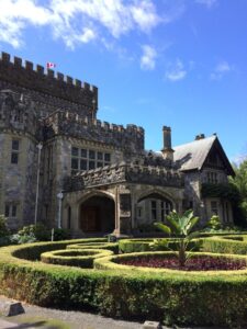 Stone turrets and arched doorways decorate Hatley Castle, framed by trimmed hedges and a round garden bed in front. Visiting this historic site adds a regal touch to any weekend trip itinerary in Victoria, BC.