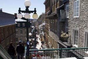 Overhead view of the pedestrian street of Le Petit Champlain, packed with people and cafes. This is one of the oldest commercial streets in North America, known for its vibrant shopping and dining scene.