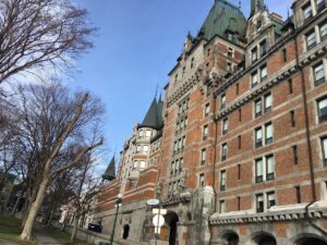 Back view of Ch&acirc;teau Frontenac in Qu&eacute;bec City, showing its turreted architecture and quiet side path lined with bare trees.