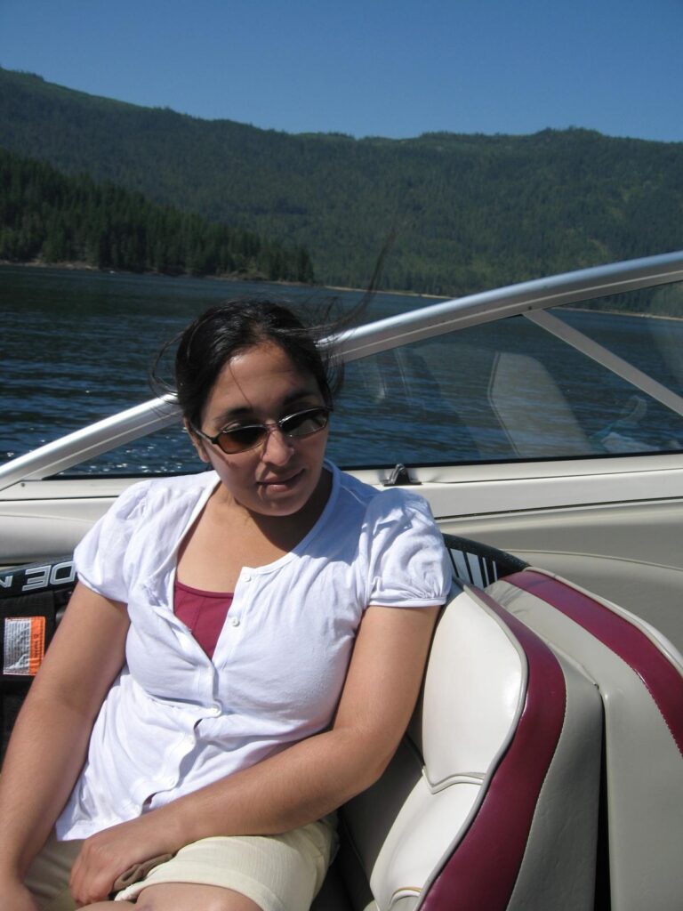 Tazim relaxes on a boat gliding over blue waters of Mara Lake near Salmon Arm, British Columbia, surrounded by scenic mountains&mdash;showcasing the variety of things to do in Salmon Arm Canada, from cruising and sightseeing to lakeside leisure.