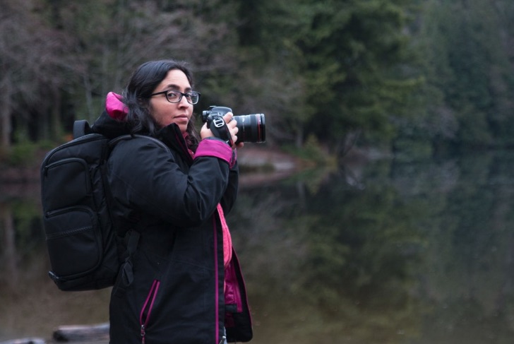 Tazim Damji - Vancouver-based travel writer with a camera at a lake in the Vancouver area.