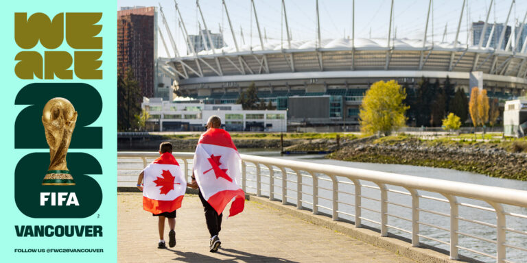Two fans draped in Canadian flags walking along False Creek towards BC Place stadium in Vancouver during World Cup 2026.
