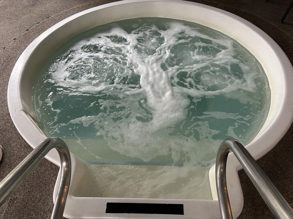 Circular indoor hot tub with bubbling water and stainless steel handrails at Quality Inn & Suites Vernon.