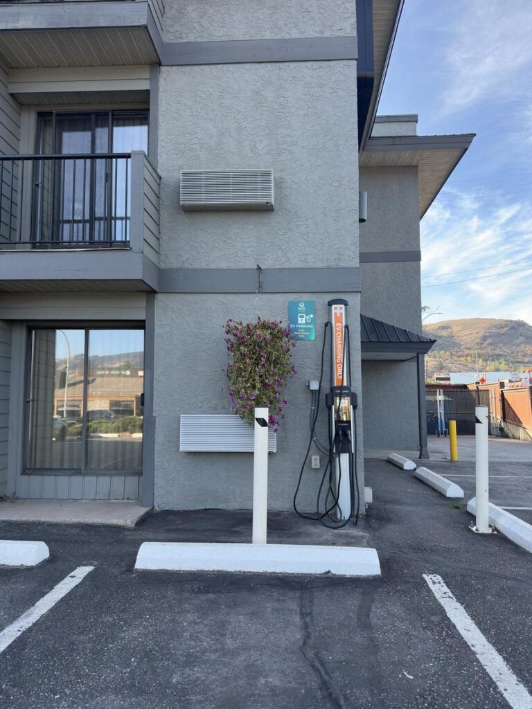 EV charging station in the parking lot of Quality Inn & Suites Vernon with signage and a hanging flower basket.