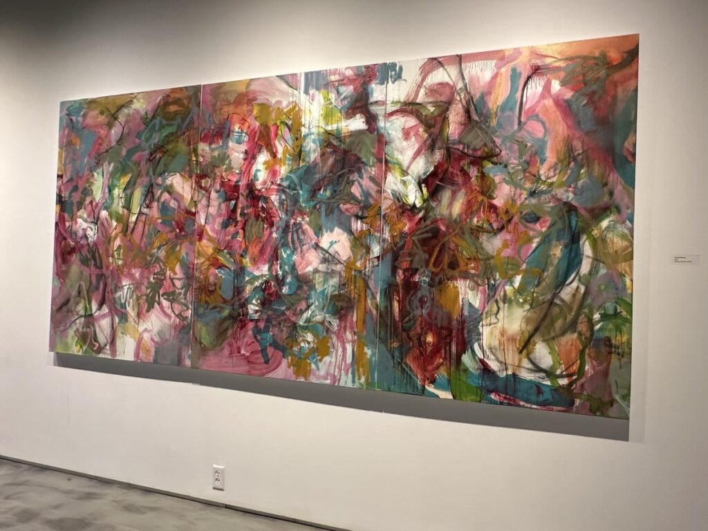 Large abstract painting in vivid pinks, greens, reds, and blues, with layered brushstrokes and gestural lines, displayed in the Vernon Public Art Gallery.