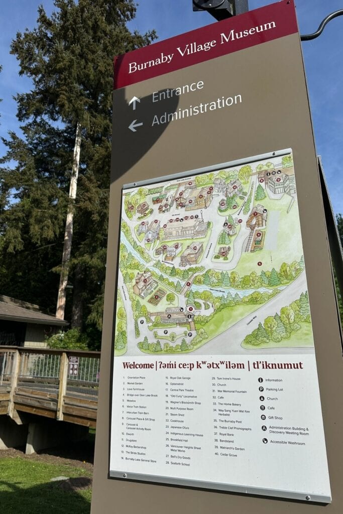 The entrance sign at Burnaby Village Museum showing a illustrated map of the grounds with numbered stops, and a welcome in English and two Indigenous languages, Burnaby, BC.