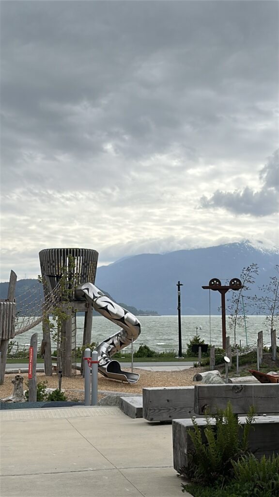 Playground beside Howe Sound at Sp'&aacute;kw'us Feather Park in Squamish, BC, with mountain views for a family-friendly soft adventure and birdwatching stop.