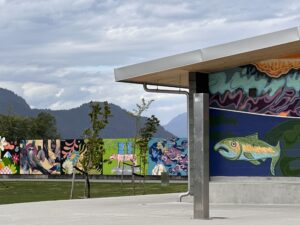 Colourful murals, mountain views, and open walking space at Sp'&aacute;kw'us Feather Park in Squamish, BC, a soft adventure stop for slow travel.