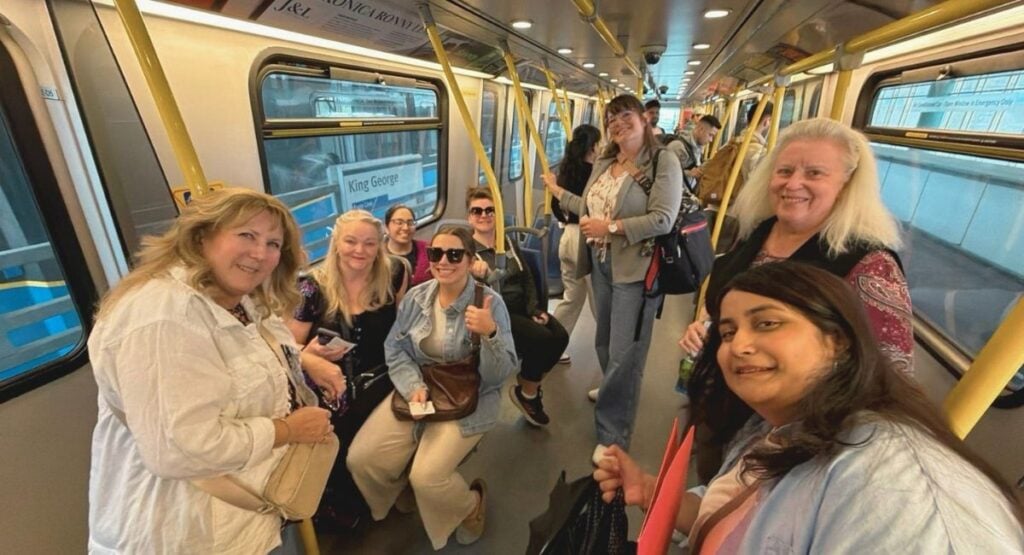 Group of women smiling on a SkyTrain car approaching King George Station in Surrey BC