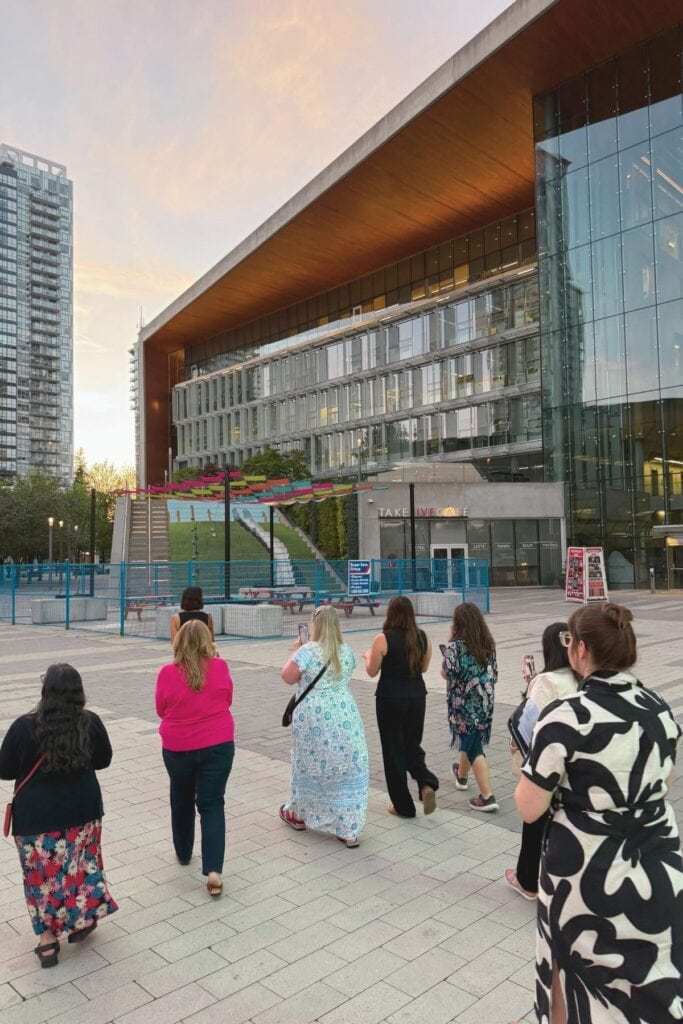Group of women walking toward the Surrey City Centre Library at dusk with Civic Plaza and surrounding towers visible in Surrey BC