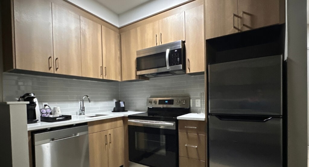 Full kitchen at Best Western Premier Route 97 Vernon with a refrigerator, stove, oven, microwave and dishwasher surrounded by light wood cabinets.