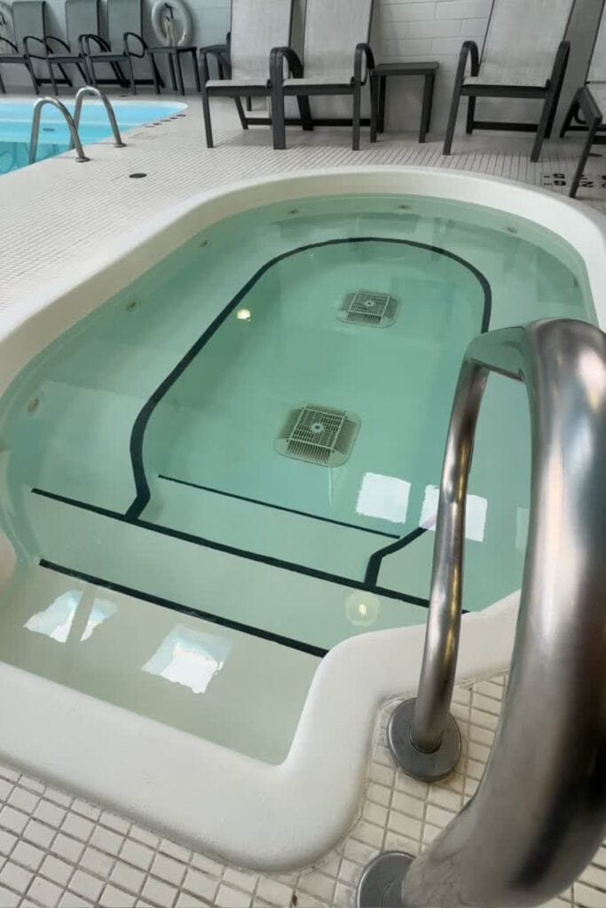 Indoor hot tub with tiled steps and a stainless steel handrail beside the swimming pool at Best Western Premier Aberdeen Kamloops. Lounge chairs line the pool area of this Kamloops hotel.