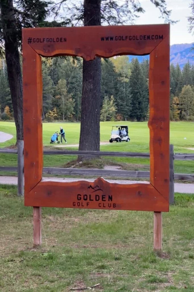 Wooden Golden Golf Club photo frame overlooking the golf course in Golden, BC, with golfers, forested mountains and early fall colours.